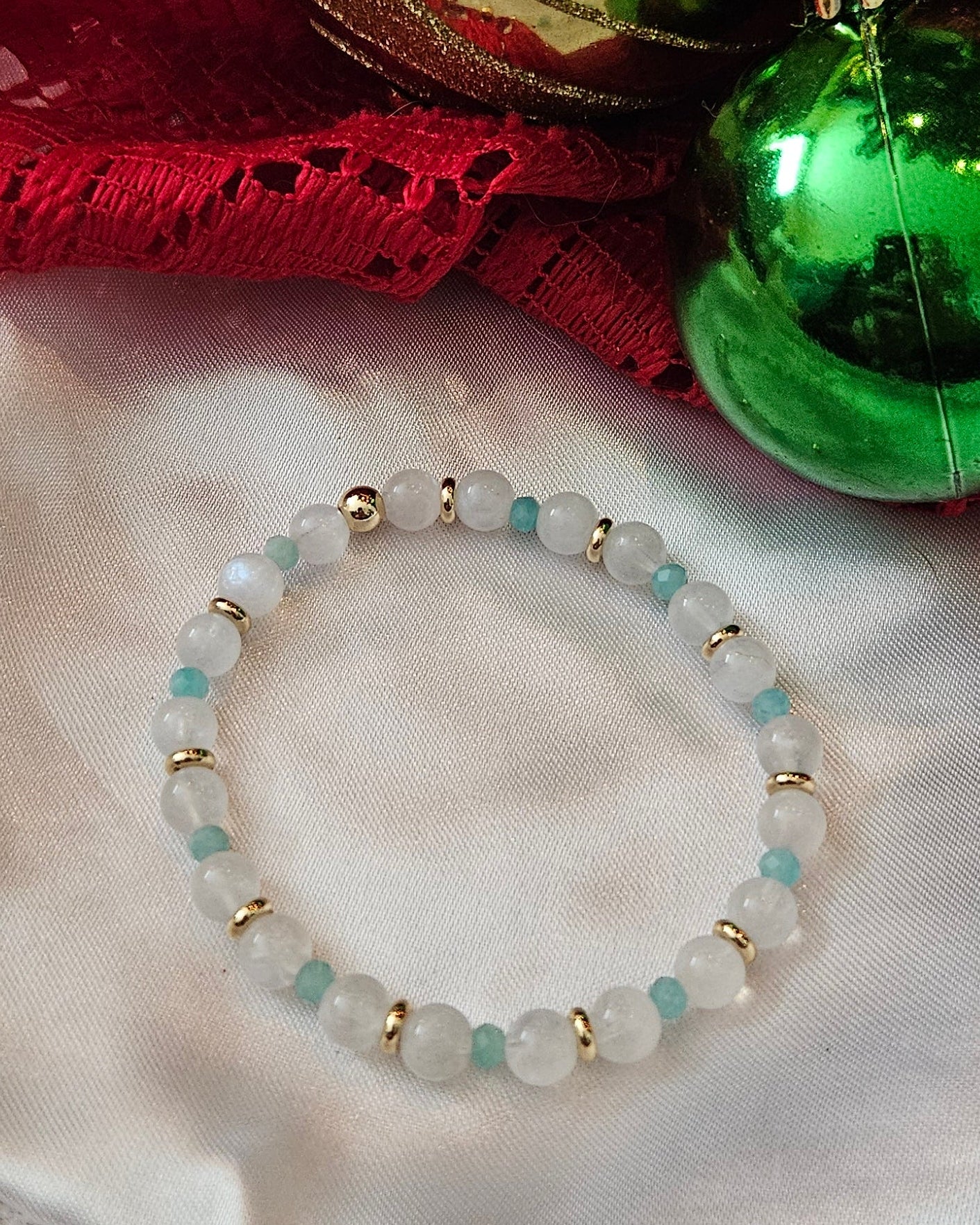 Decorative gold and green ornaments with a bracelet on a textured surface