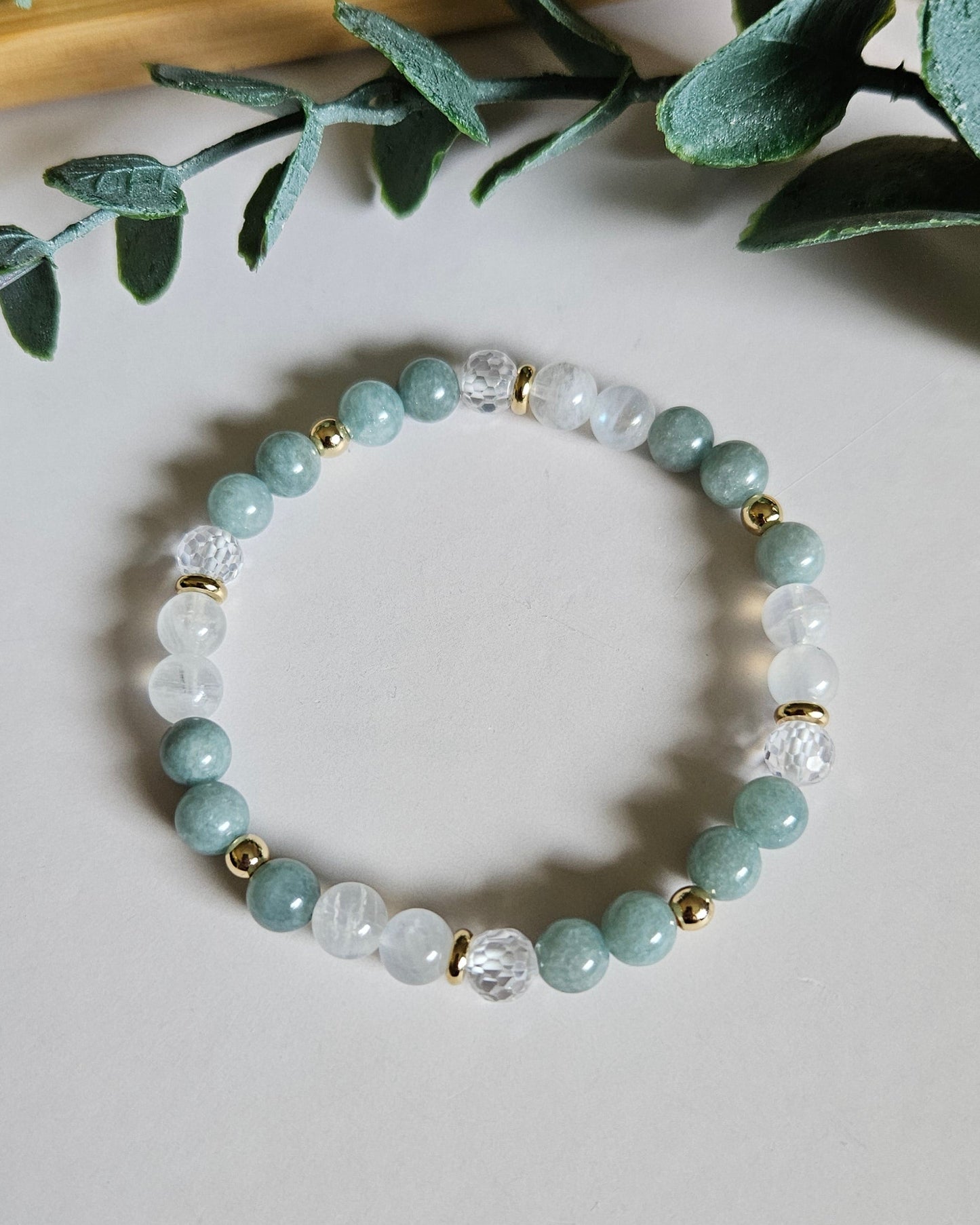 Beaded bracelet on a light surface with green leaves in the background