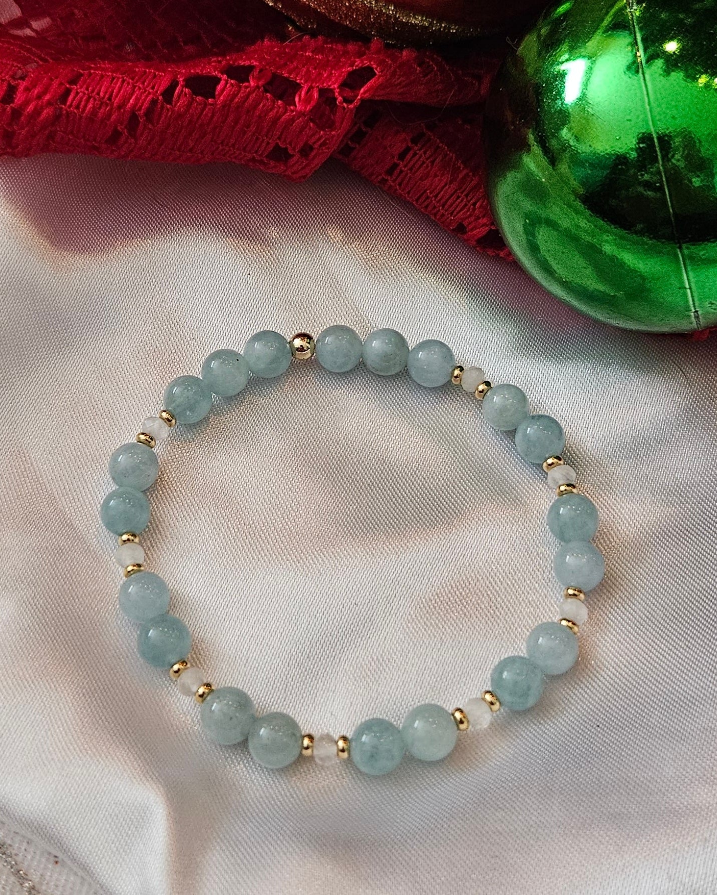 Bracelet on a textured fabric surface with decorative Christmas ornaments.