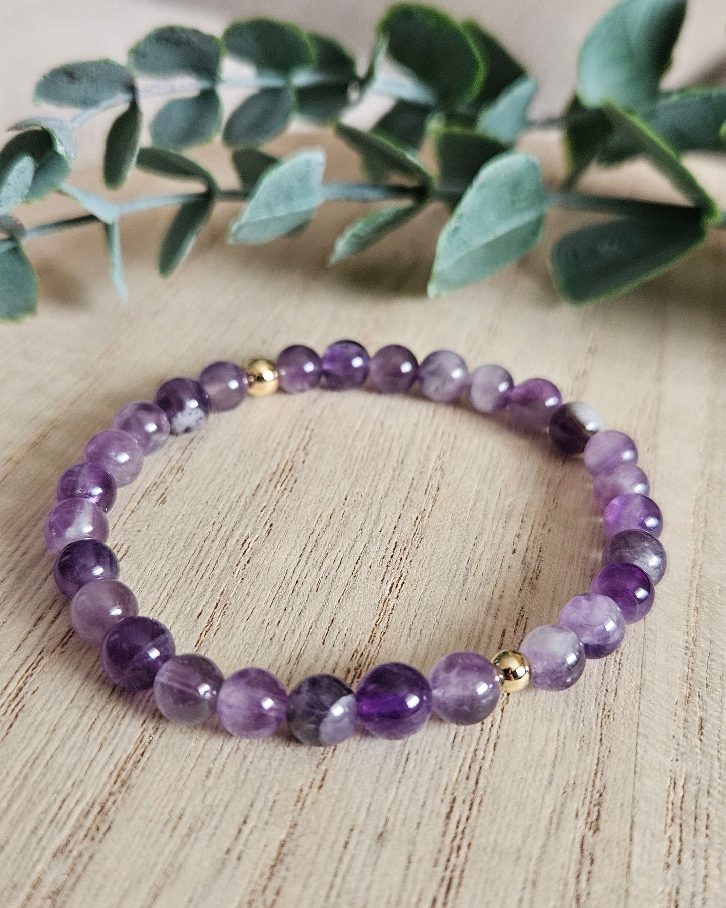 Amethyst bracelet on a wooden surface with greenery