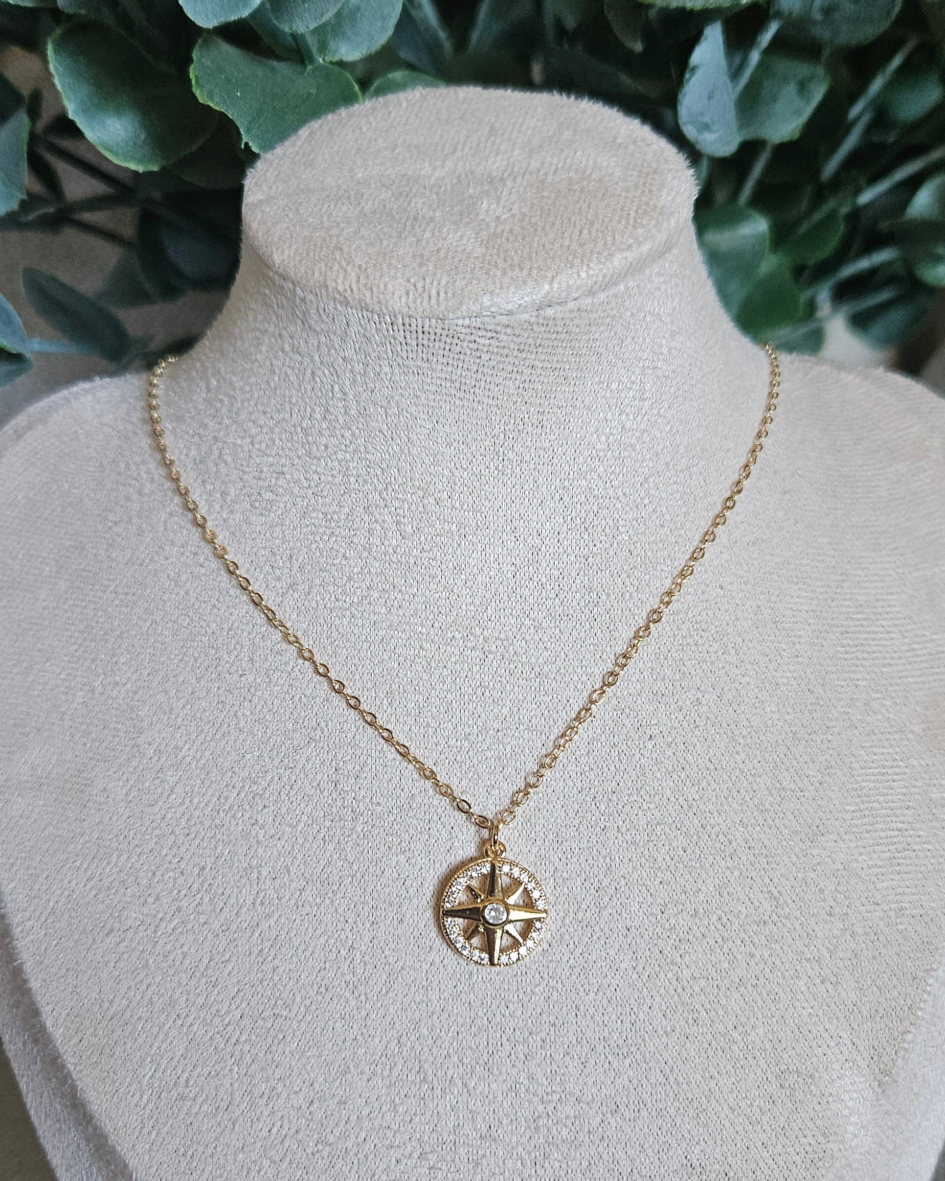 Gold necklace with a heart pendant on a white mannequin bust against a natural background.