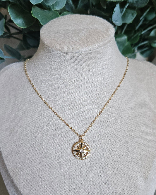 Gold necklace with a heart pendant on a white mannequin bust against a natural background.