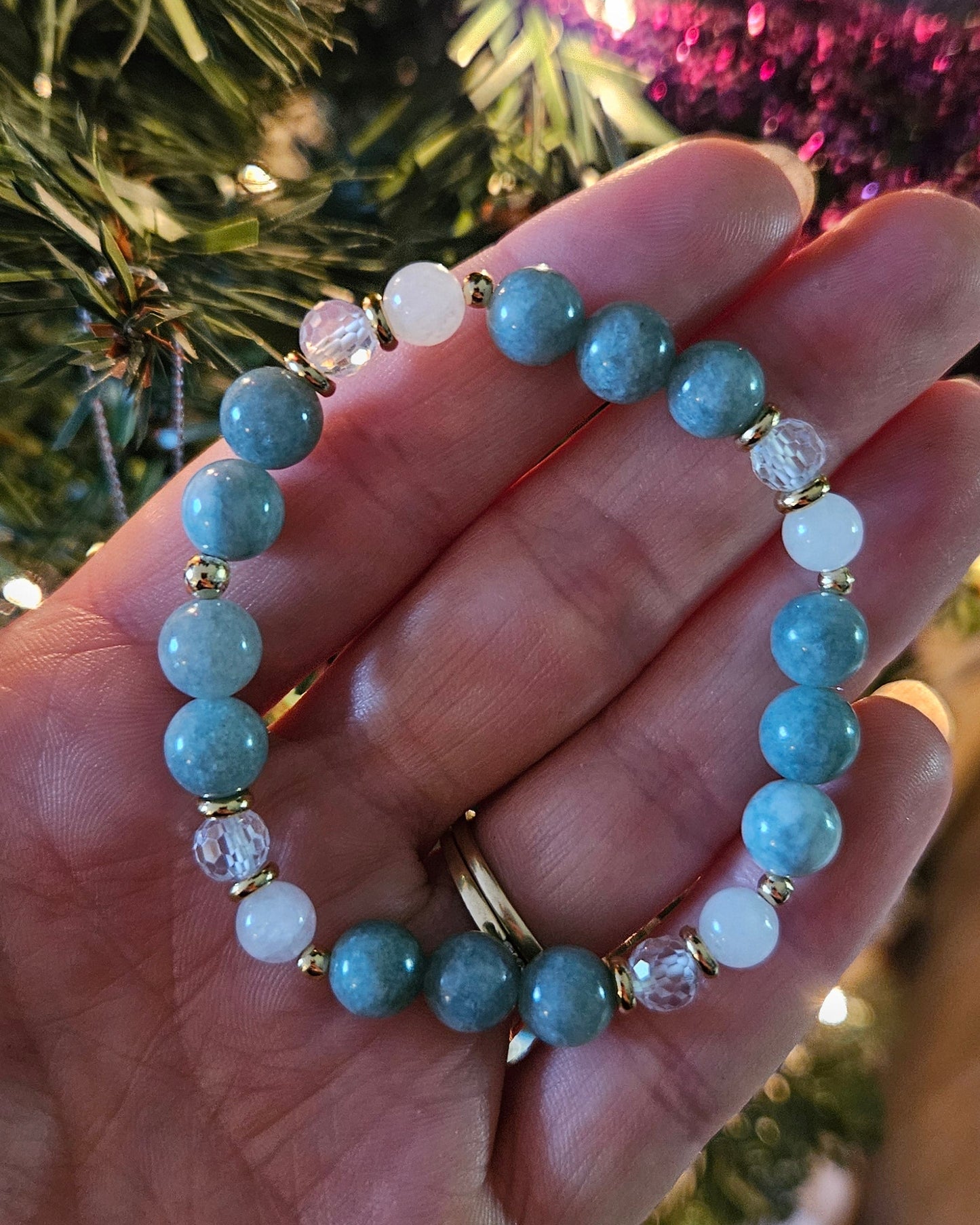 Hand holding two beaded bracelets with a festive background