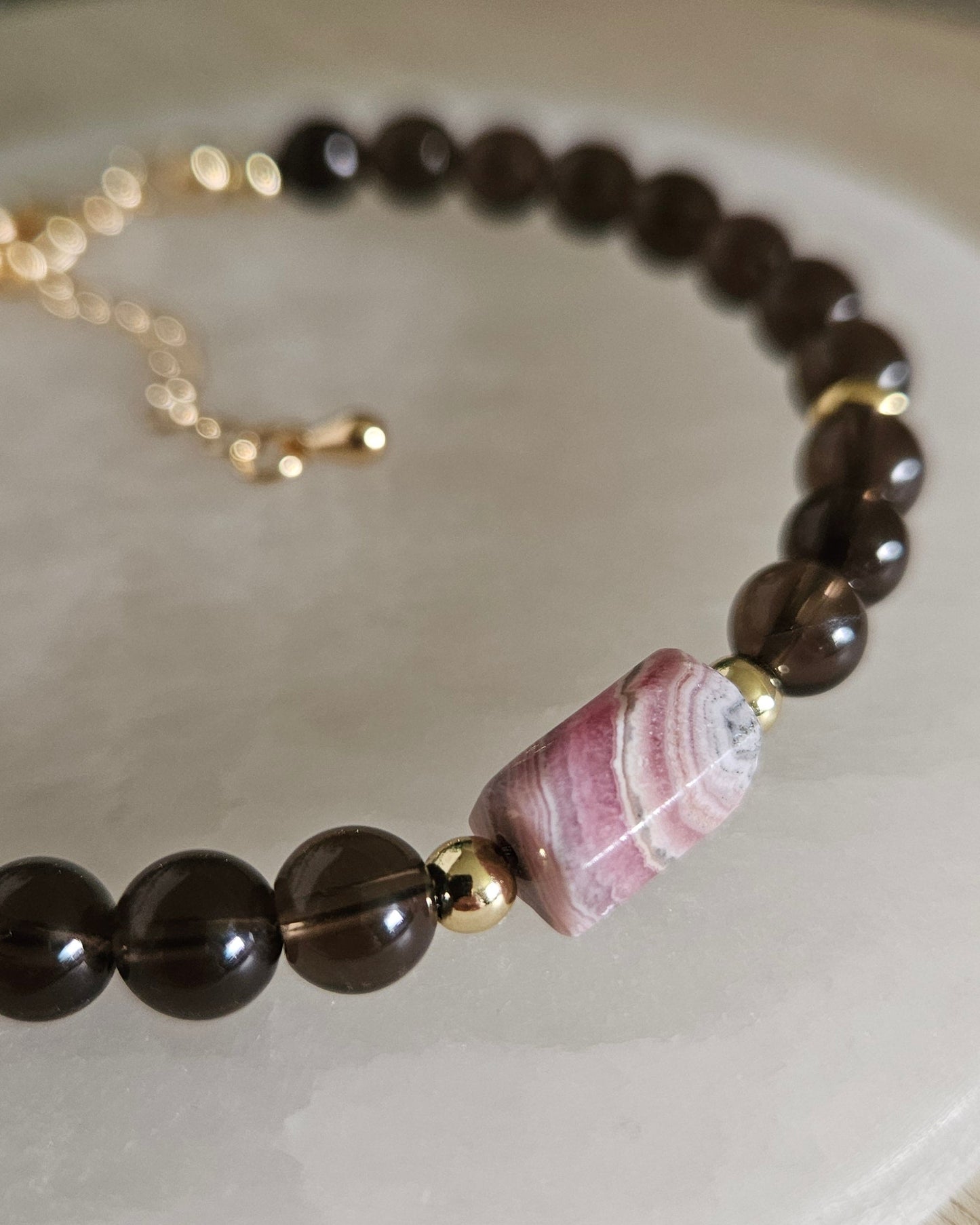 Close-up of the pink-and-white banded Rhodochrosite focal, translucent Smoky Quartz beads and gold accents