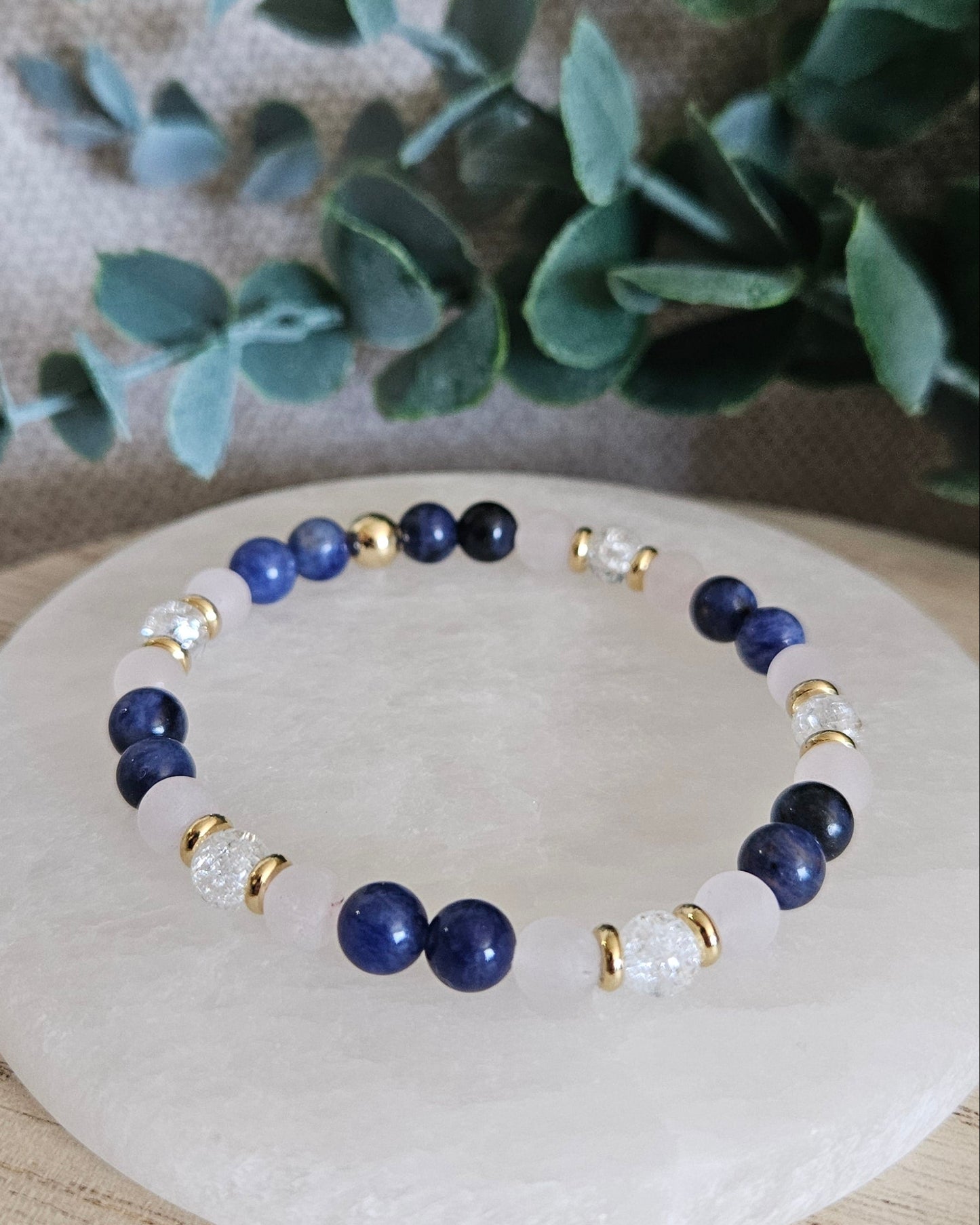 Close view of the blue Sodalite, pale pink Rose Quartz and cracked Clear Quartz bracelet on a selenite plate