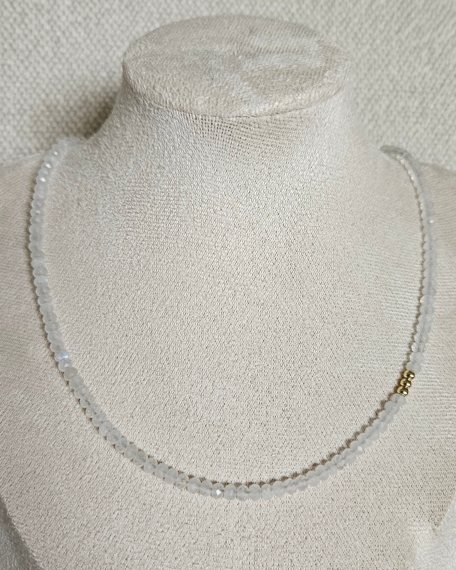 Faceted Moonstone rondelle necklace with gold-plated accents displayed on a beige jewellery bust