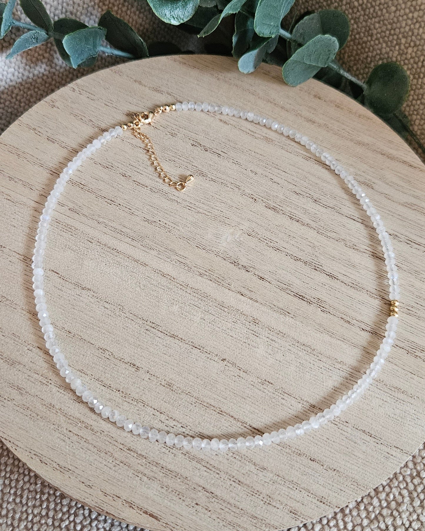 Full Moonstone necklace with gold-plated clasp and extender chain arranged on a round wooden display