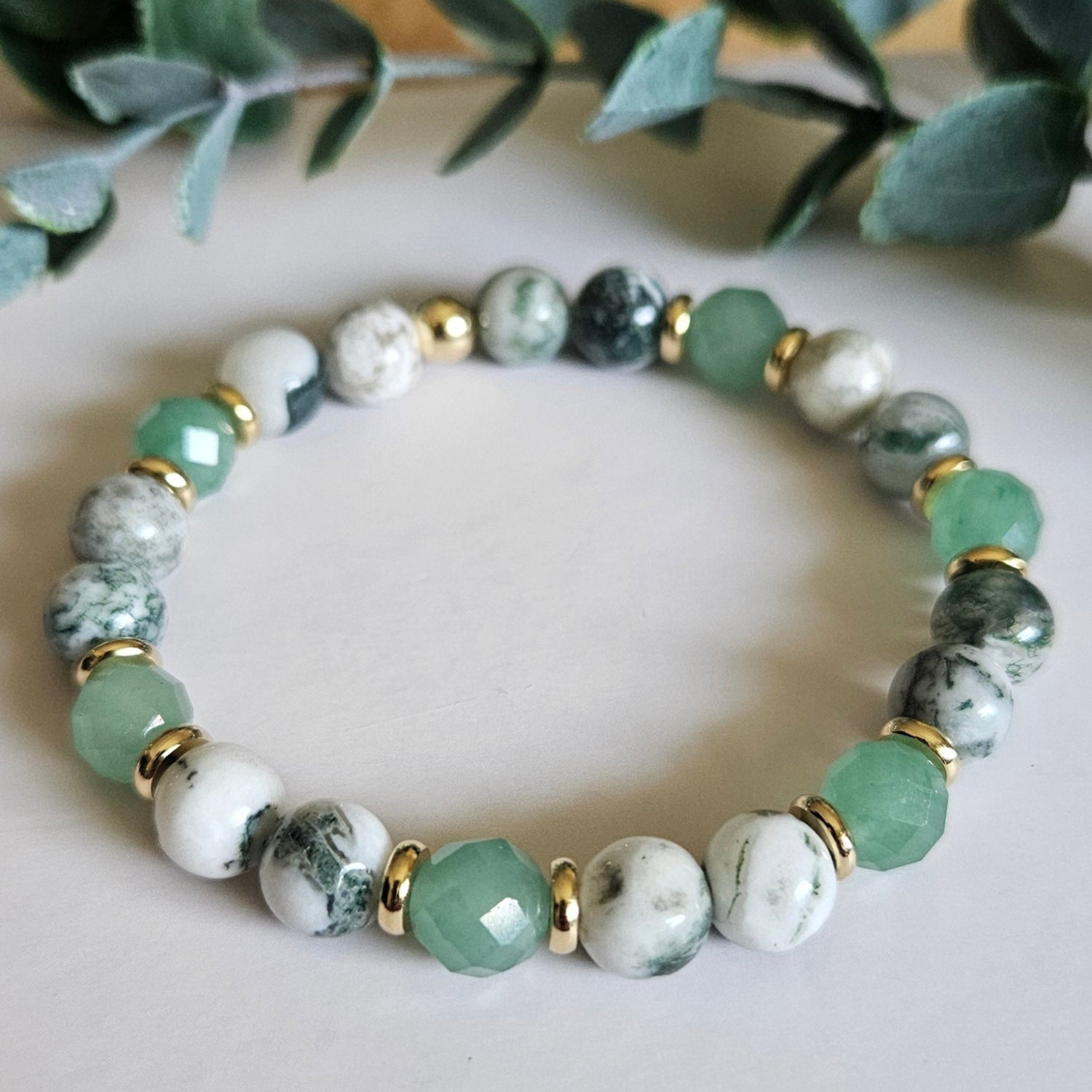 Beaded bracelet with green and white stones on a neutral background