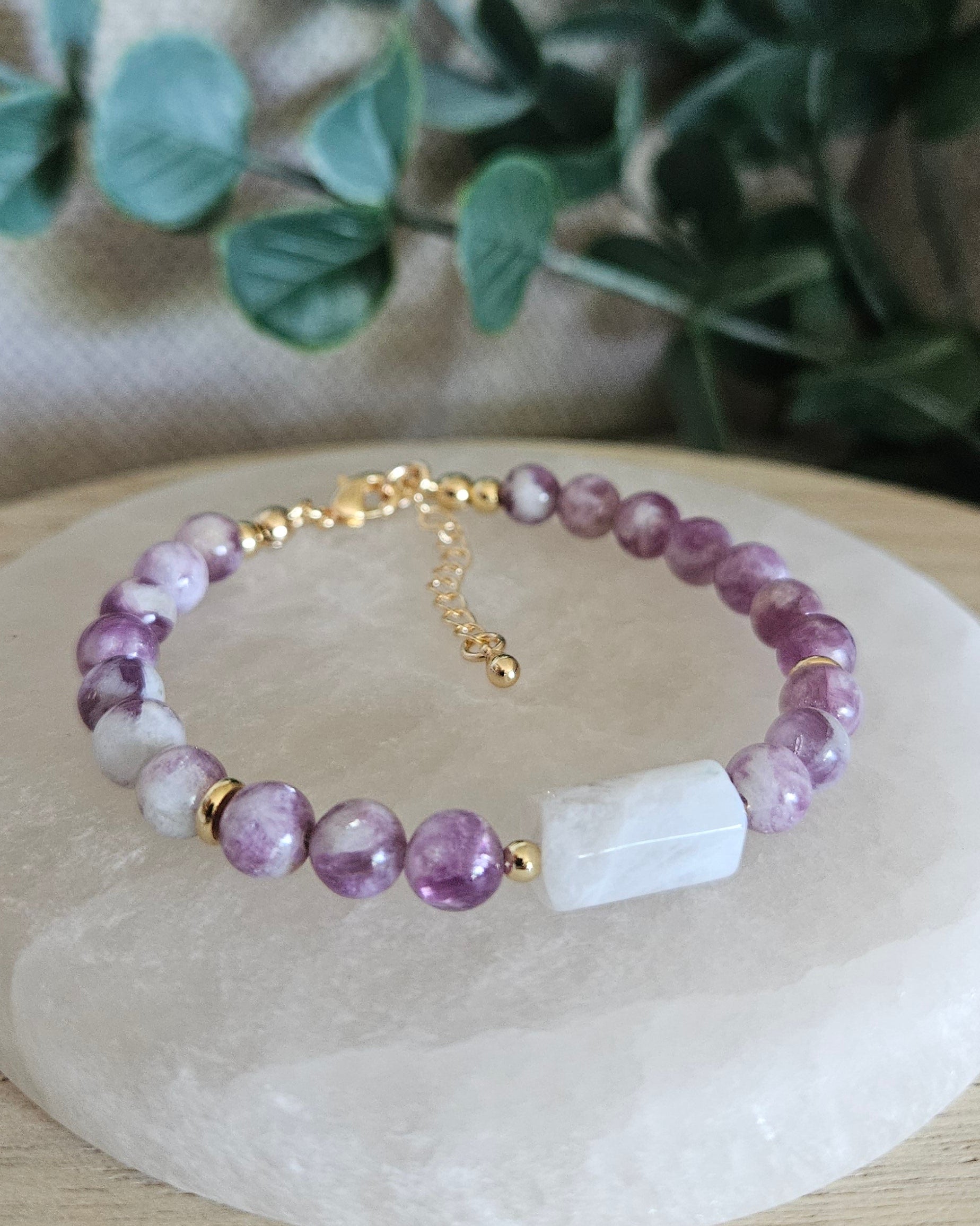 Lepidolite bracelet with a rectangular Moonstone focal, gold-plated accents and extender chain displayed on selenite