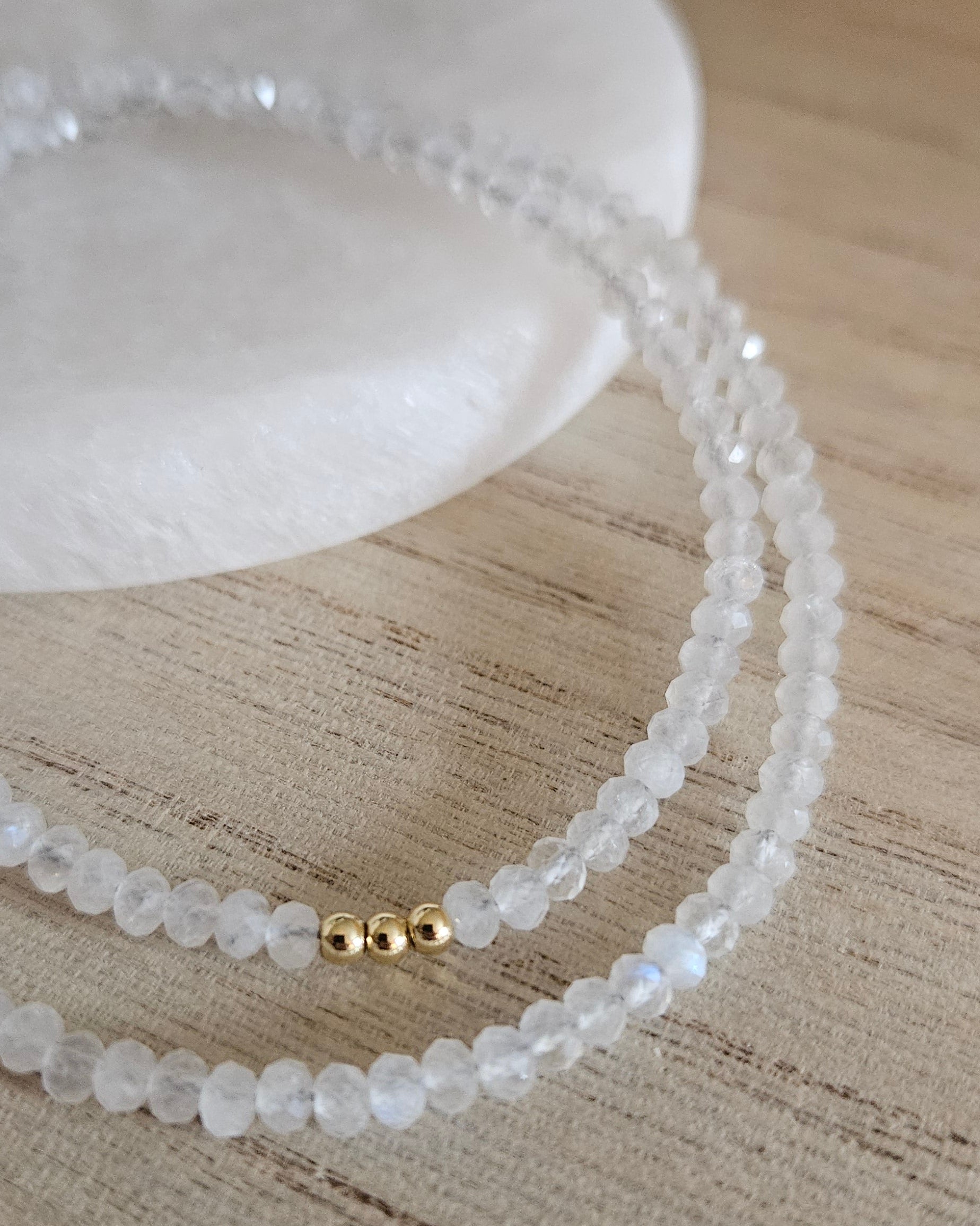 Macro close-up of faceted Moonstone rondelle beads and three polished gold-plated accent beads
