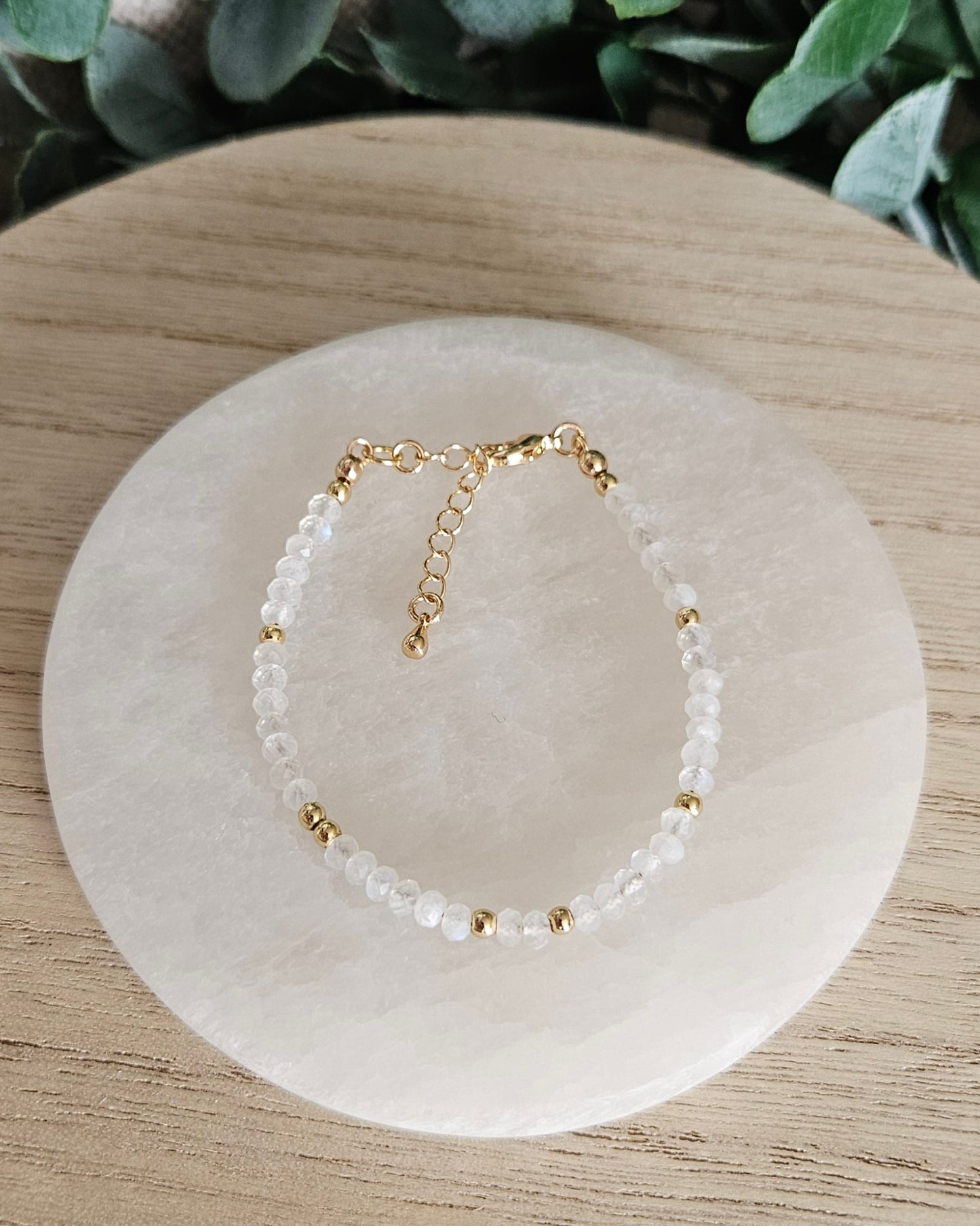 Overhead view of the adjustable Moonstone bracelet with gold-plated clasp and extender chain on selenite
