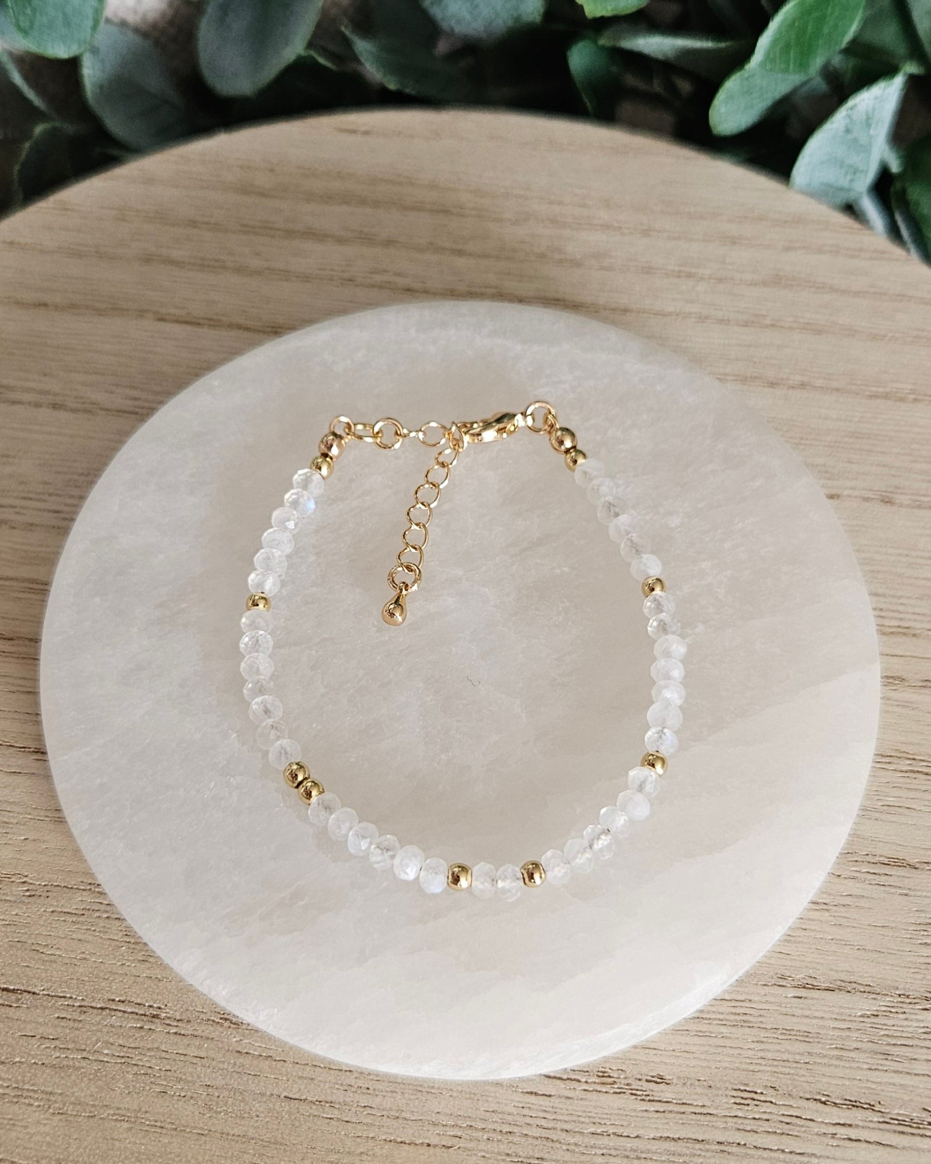 Overhead view of the adjustable Moonstone bracelet with gold-plated clasp and extender chain on selenite
