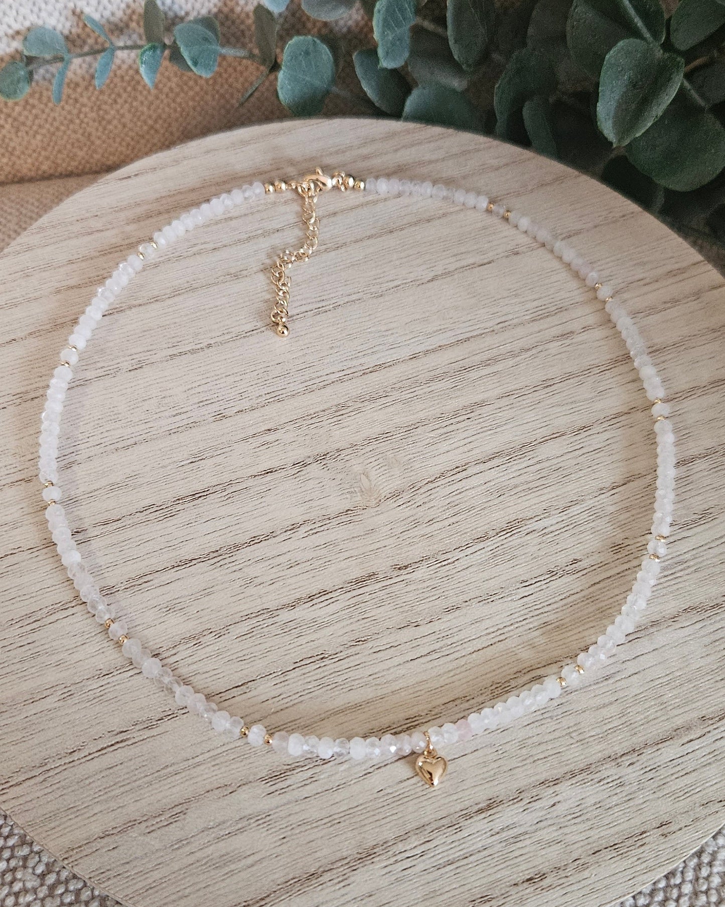 Overhead view of the complete Rose Quartz heart necklace arranged on a round wooden display