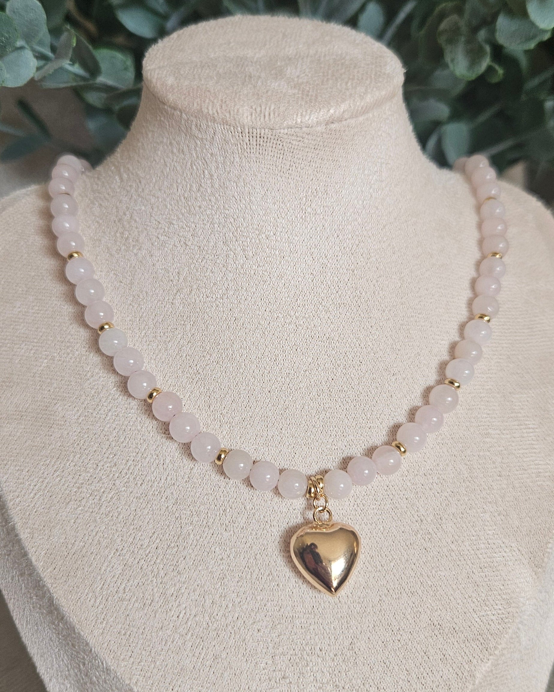 Front view of the Rose Quartz bead necklace with a 14k gold-filled heart pendant displayed on a beige jewellery bust