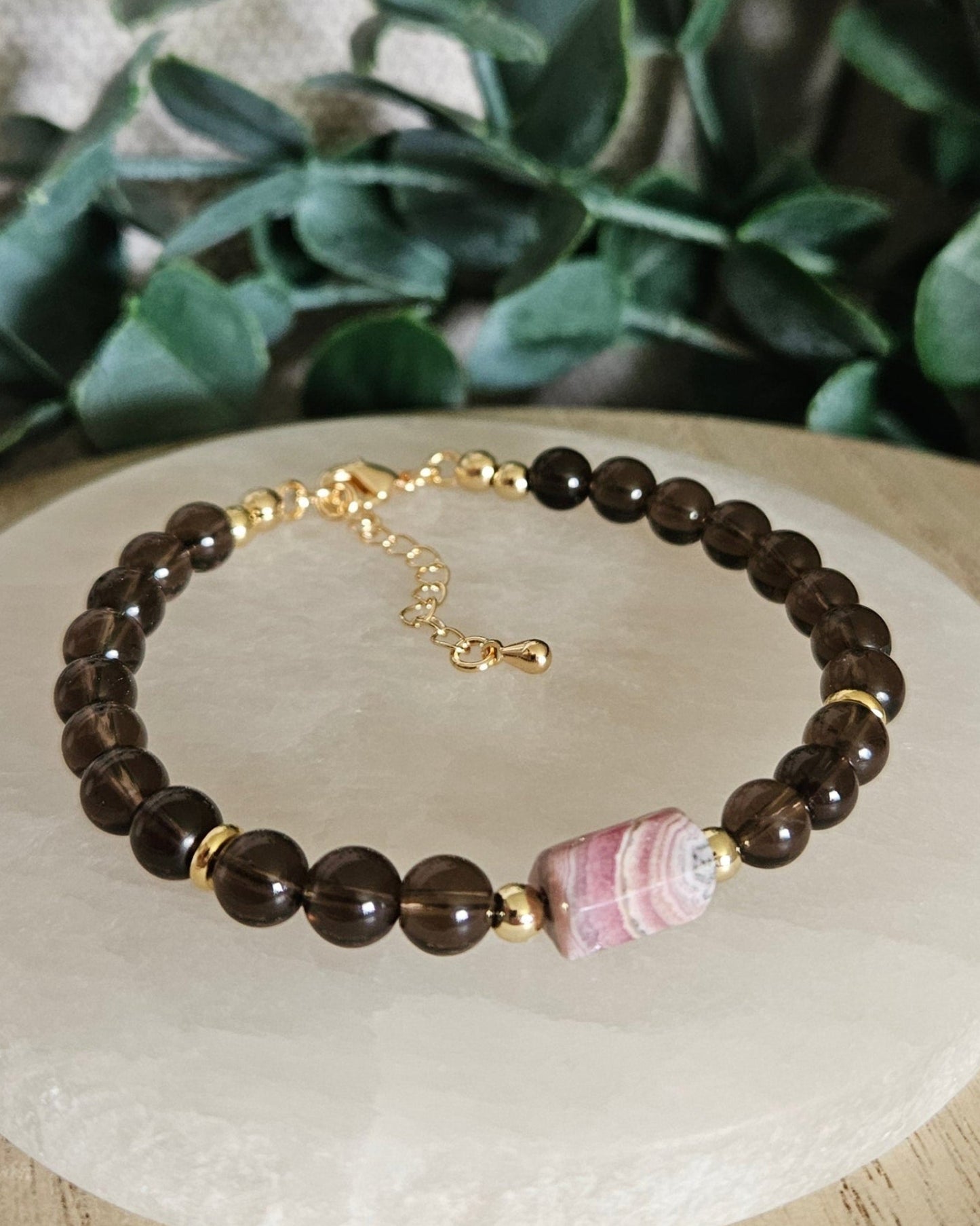 Smoky Quartz bracelet with a banded pink Rhodochrosite focal, gold-plated accents and extender chain on selenite