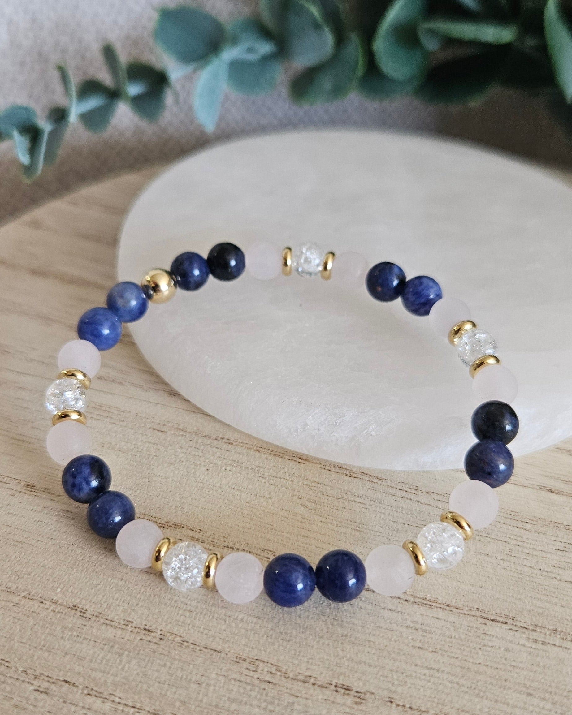 Sodalite, matte Rose Quartz and cracked Clear Quartz stretch bracelet with gold spacers arranged before selenite