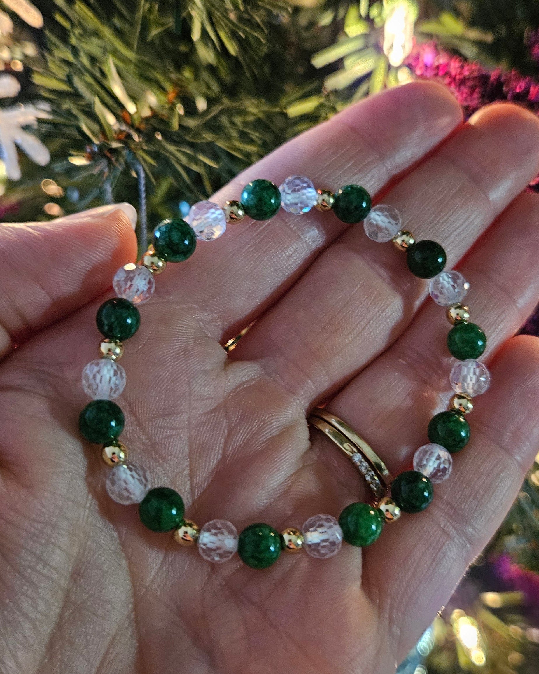 Hand holding a green beaded bracelet with a blurred festive background