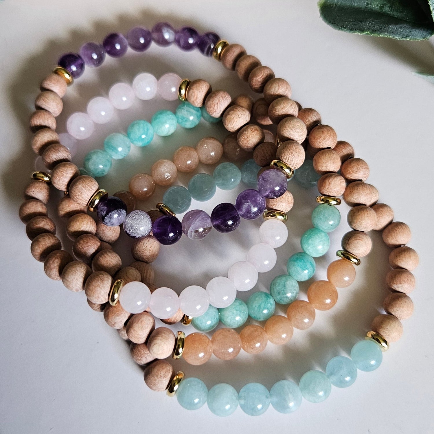 Set of beaded bracelets on a white surface with green leaves in the background