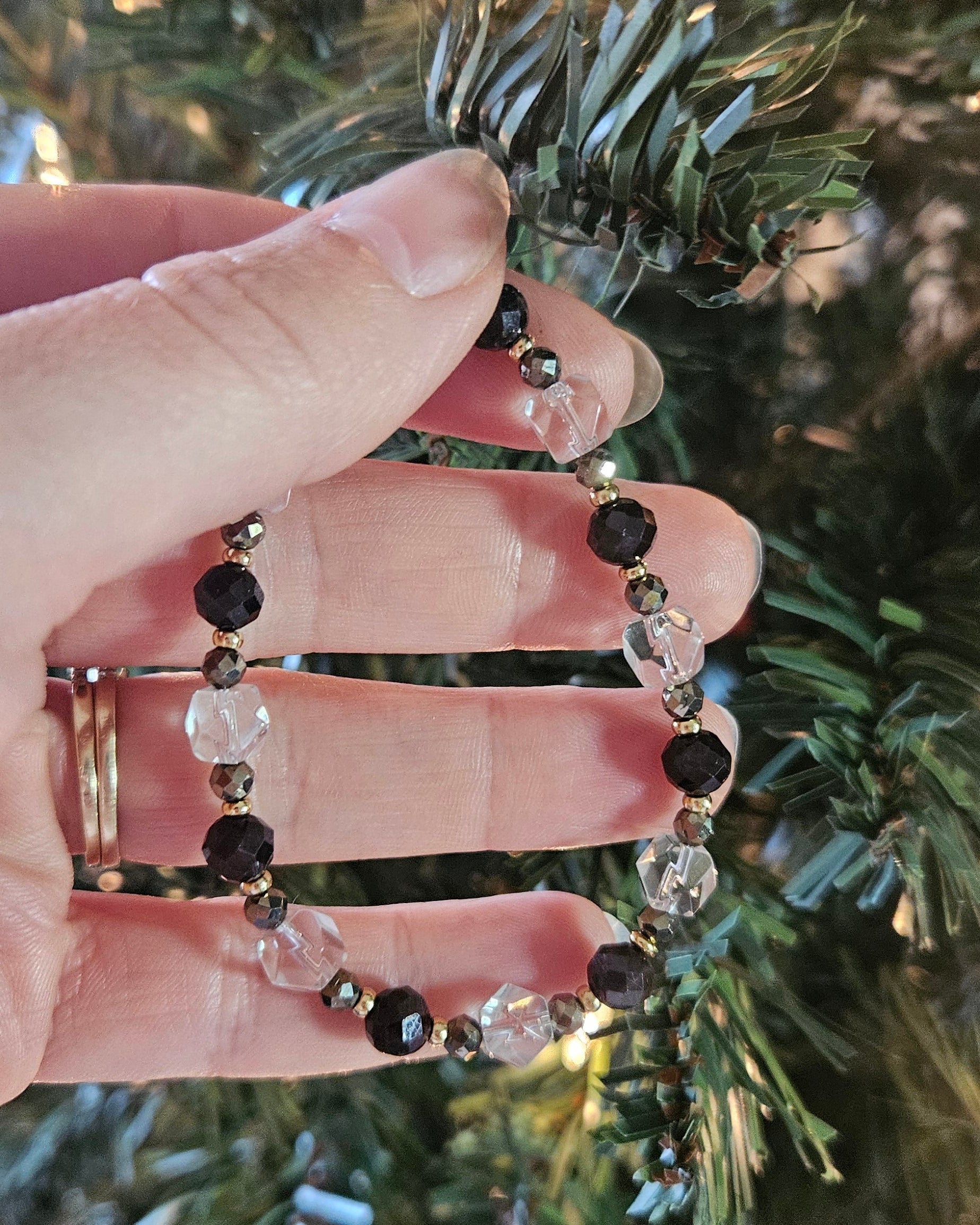 Hand wearing a bracelet with red and clear beads against a festive background