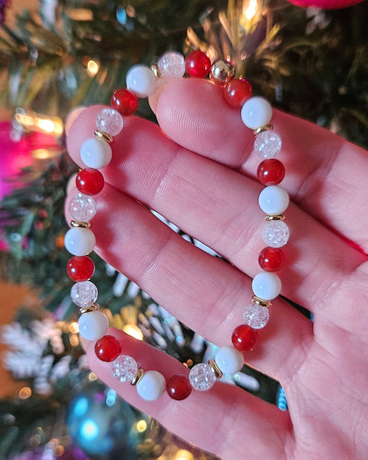 Hand holding a beaded bracelet with a Christmas tree background