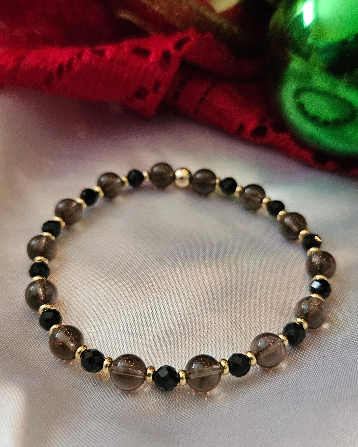 Bracelet with black and gold beads on a white fabric background