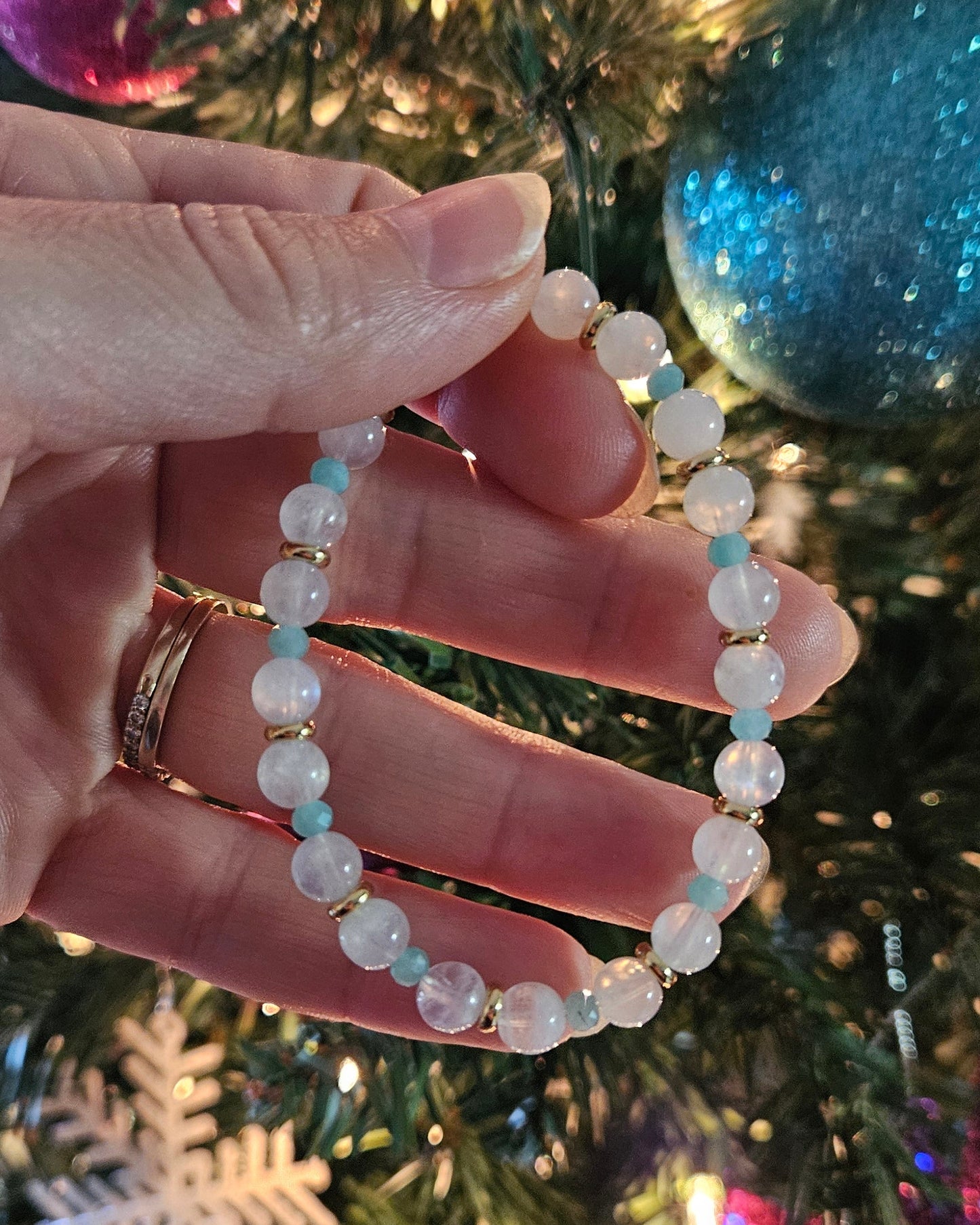 Hand holding a beaded bracelet with a Christmas tree in the background