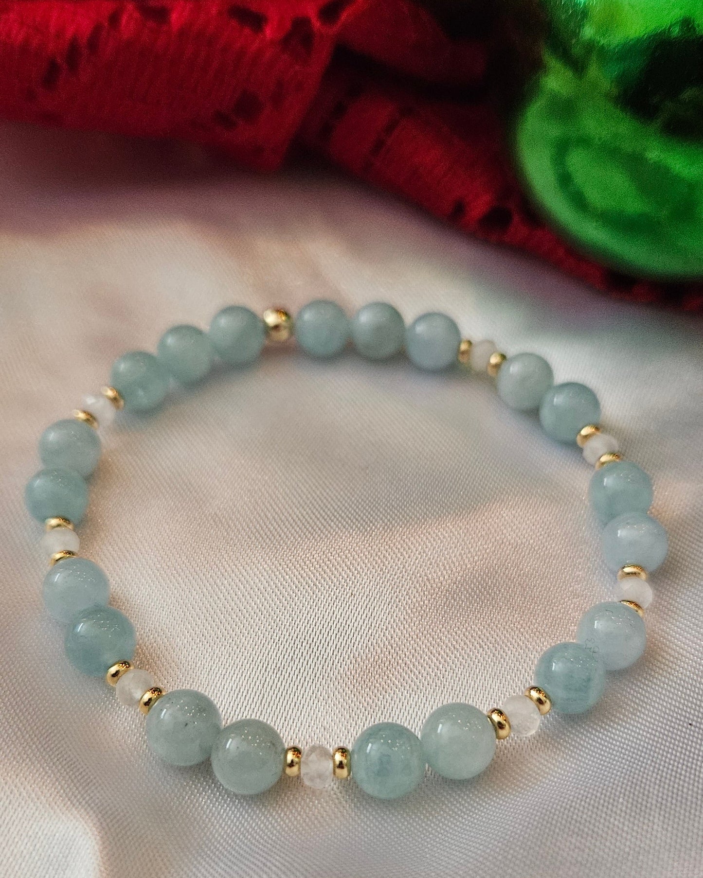 Light blue beaded bracelet with gold accents on a white fabric background