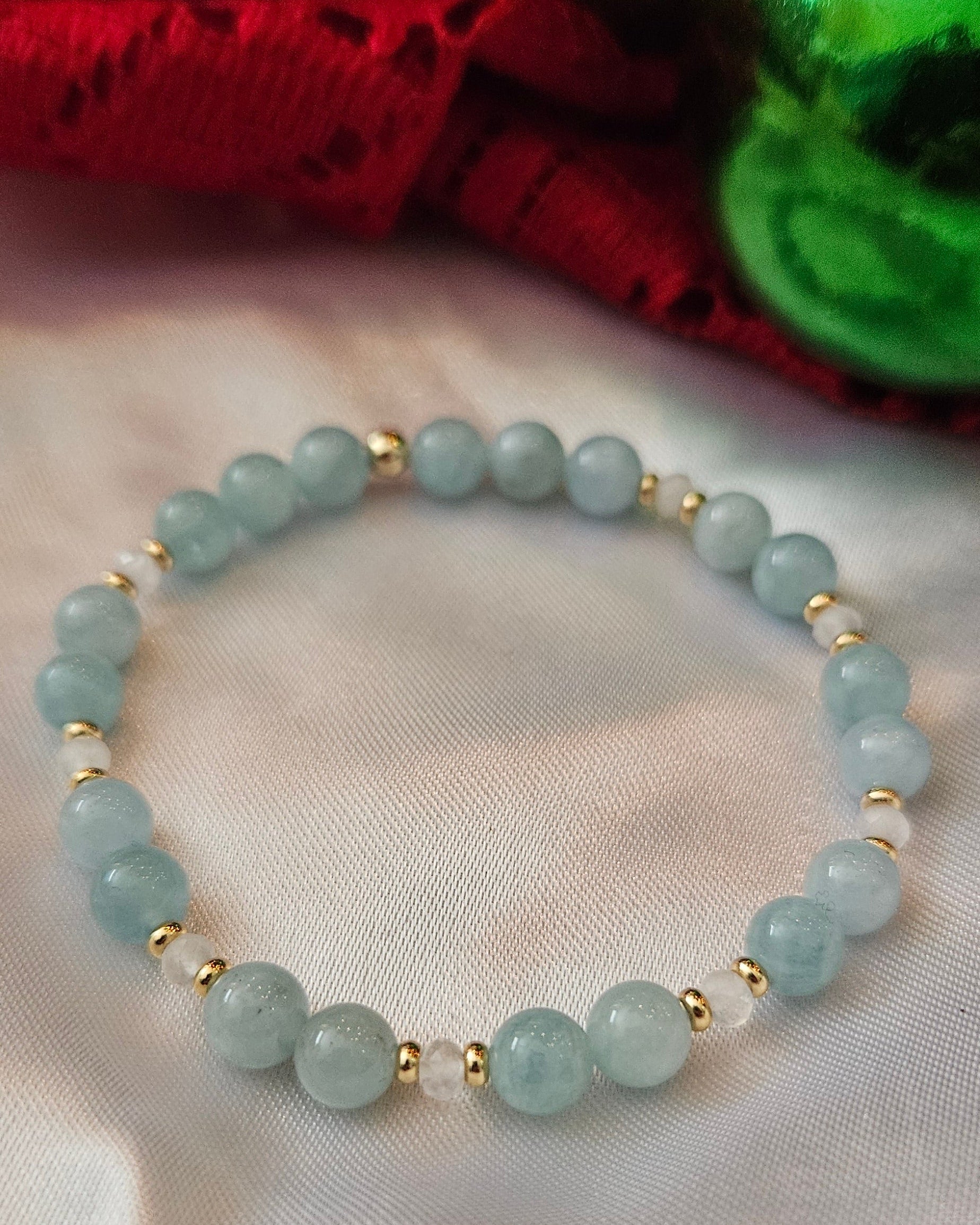 Light blue beaded bracelet with gold accents on a white fabric background
