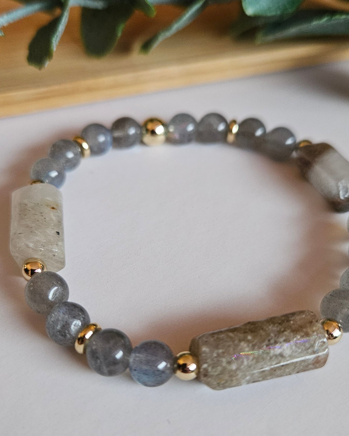 Bracelet with gray beads and gold accents on a light background