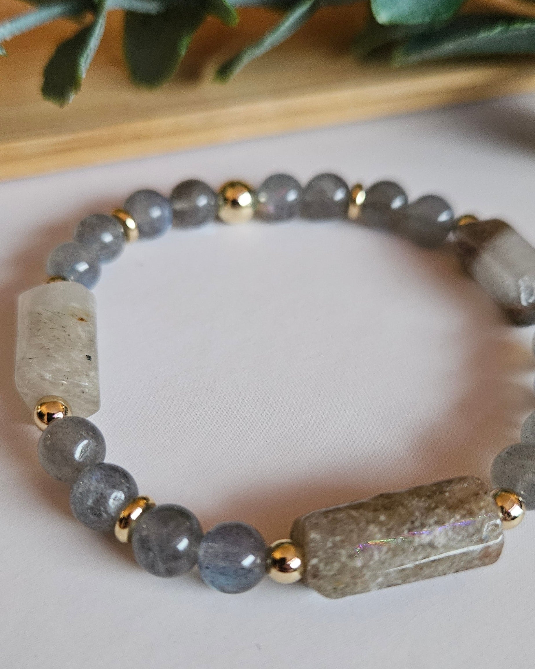 Bracelet with gray beads and gold accents on a light background