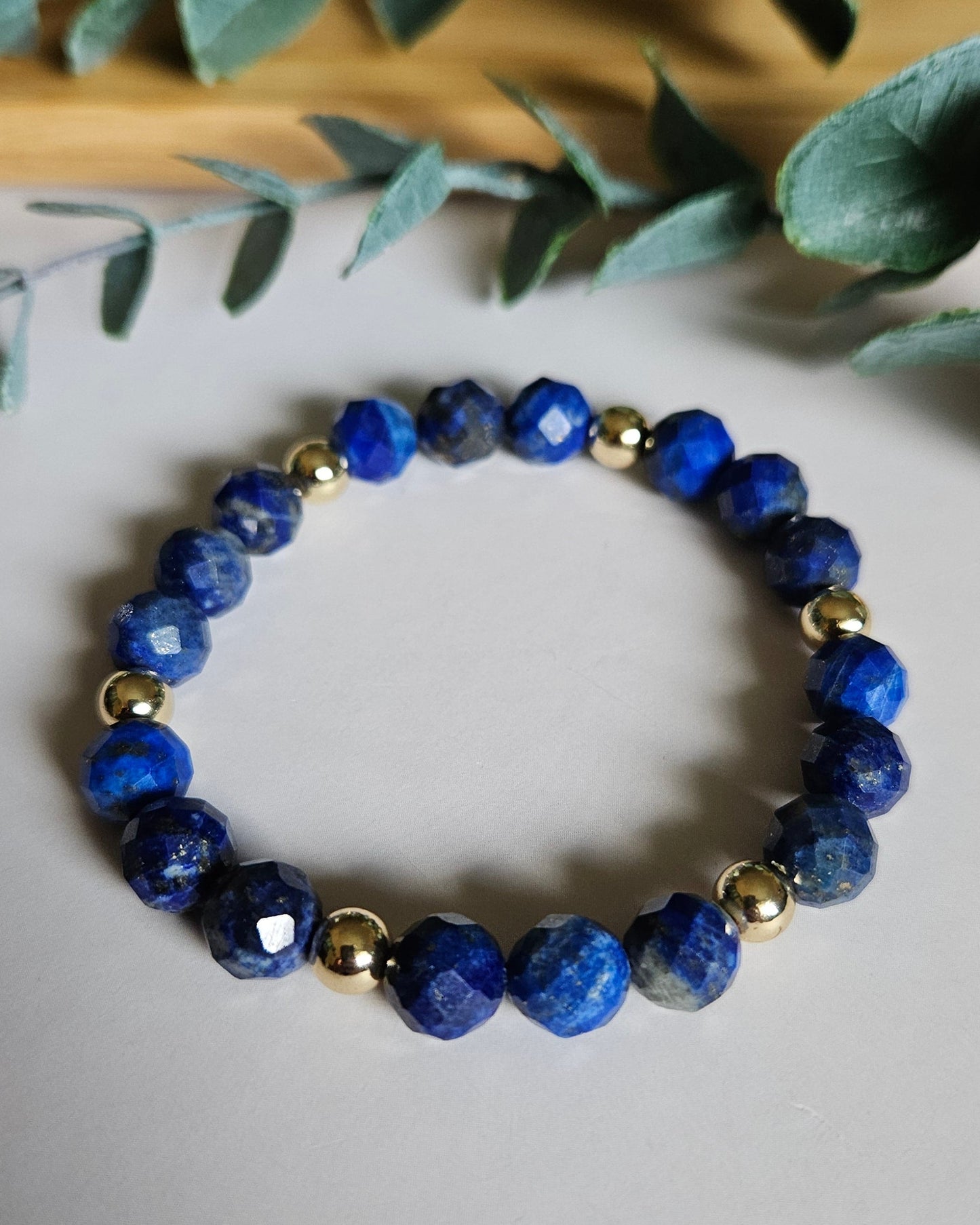 Blue beaded bracelet on a light background with green leaves