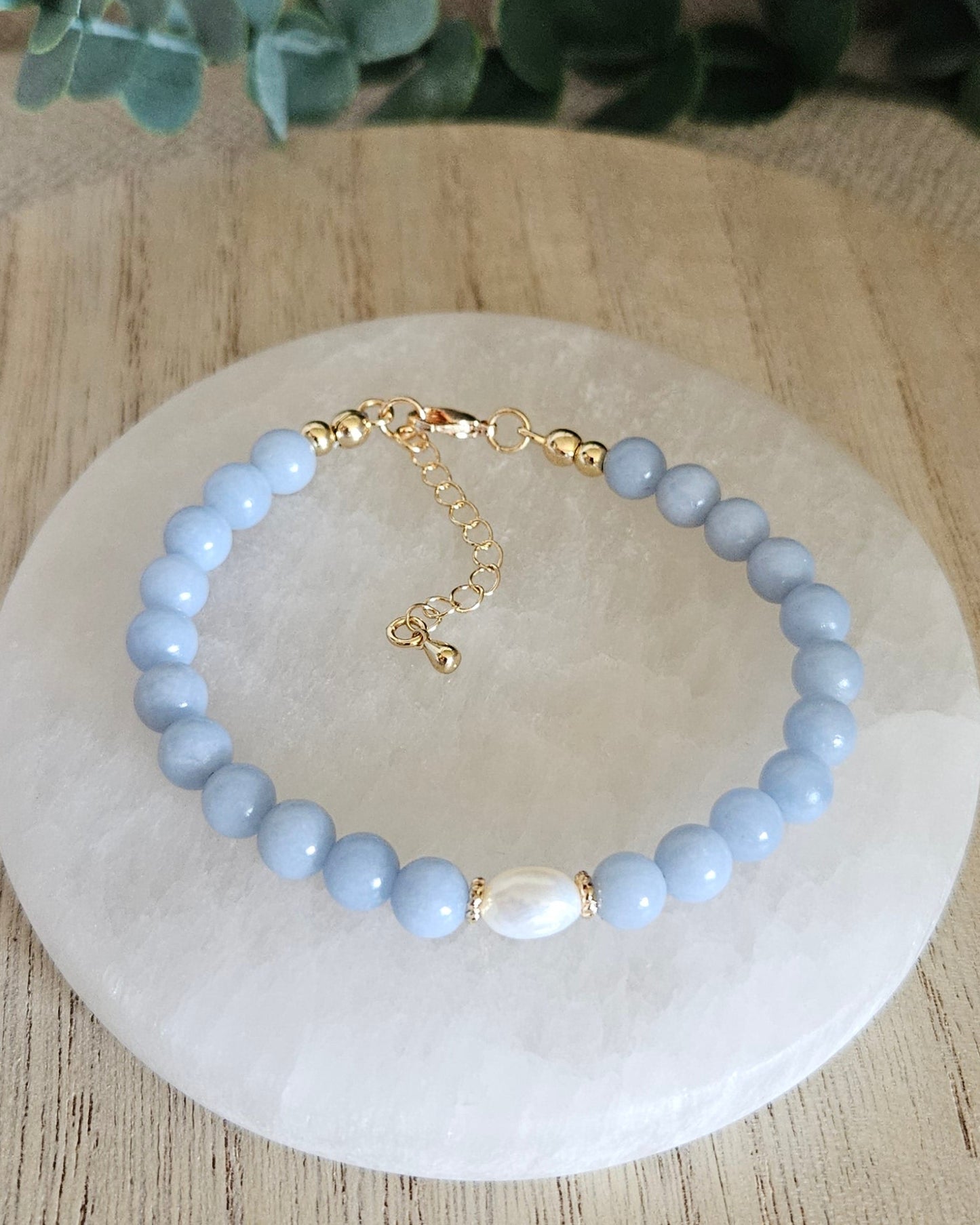 angelite bracelet with freshwater pearl on selenite plate and eucalyptus in the background