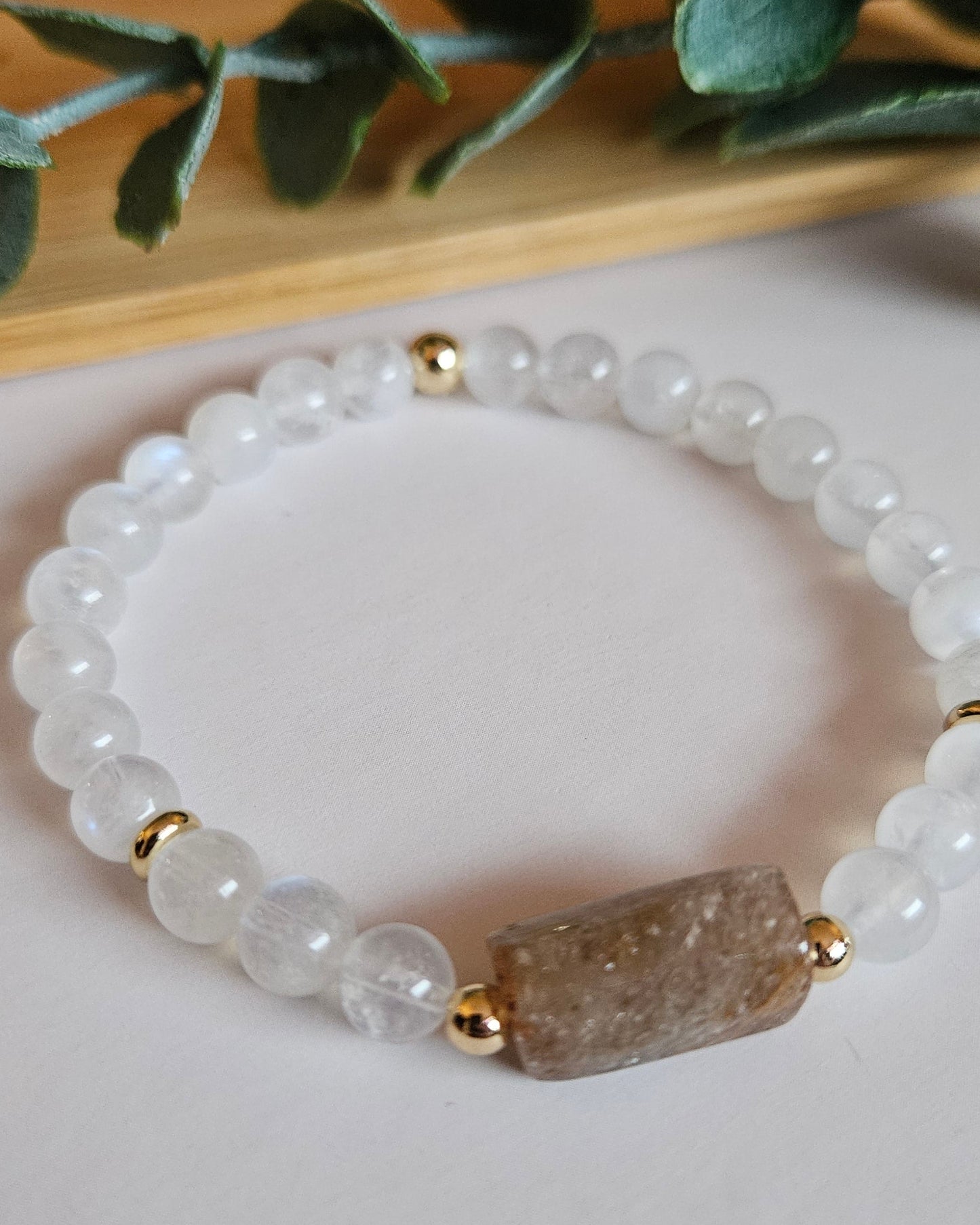 Bracelet with white beads and a brown stone on a light background