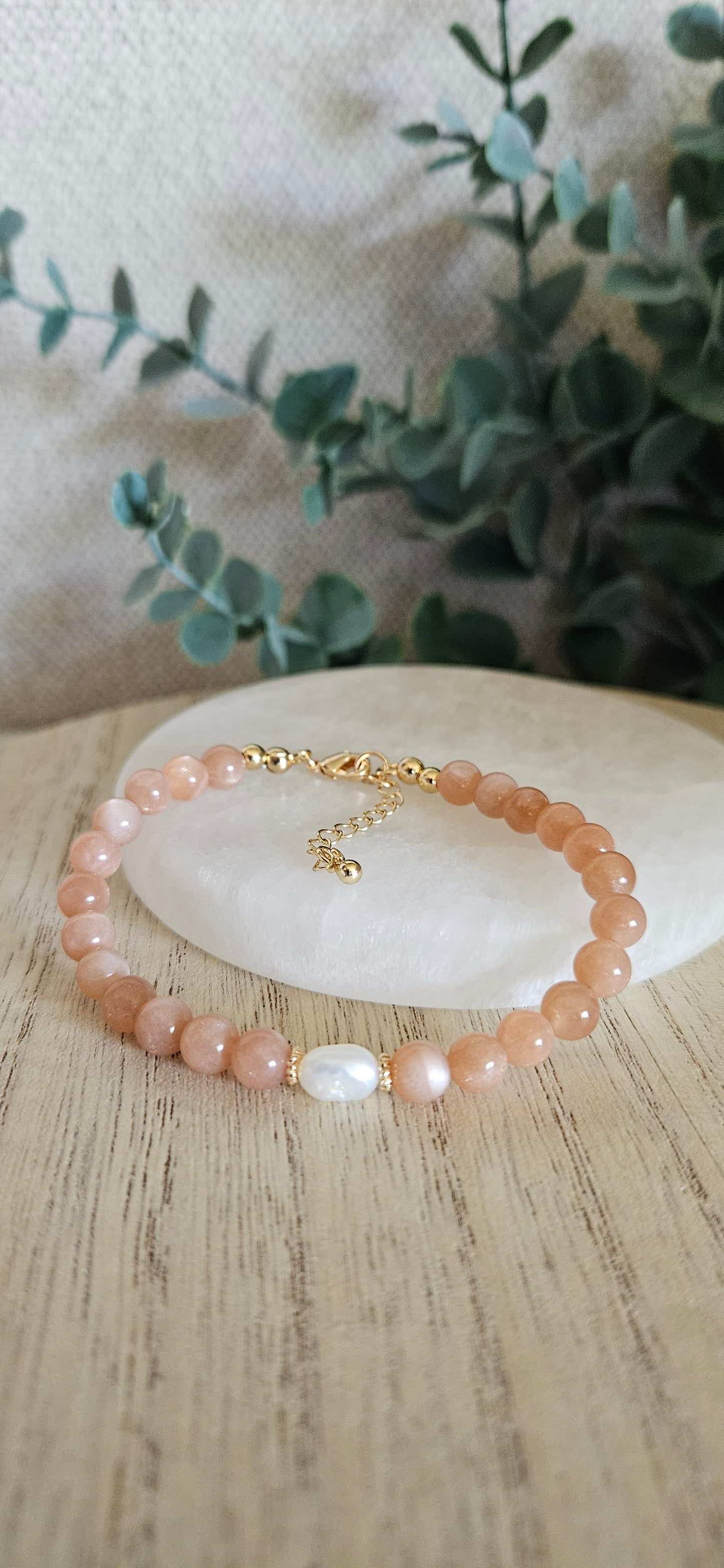 orange gemstone bracelet with a pearl on a selenite plate