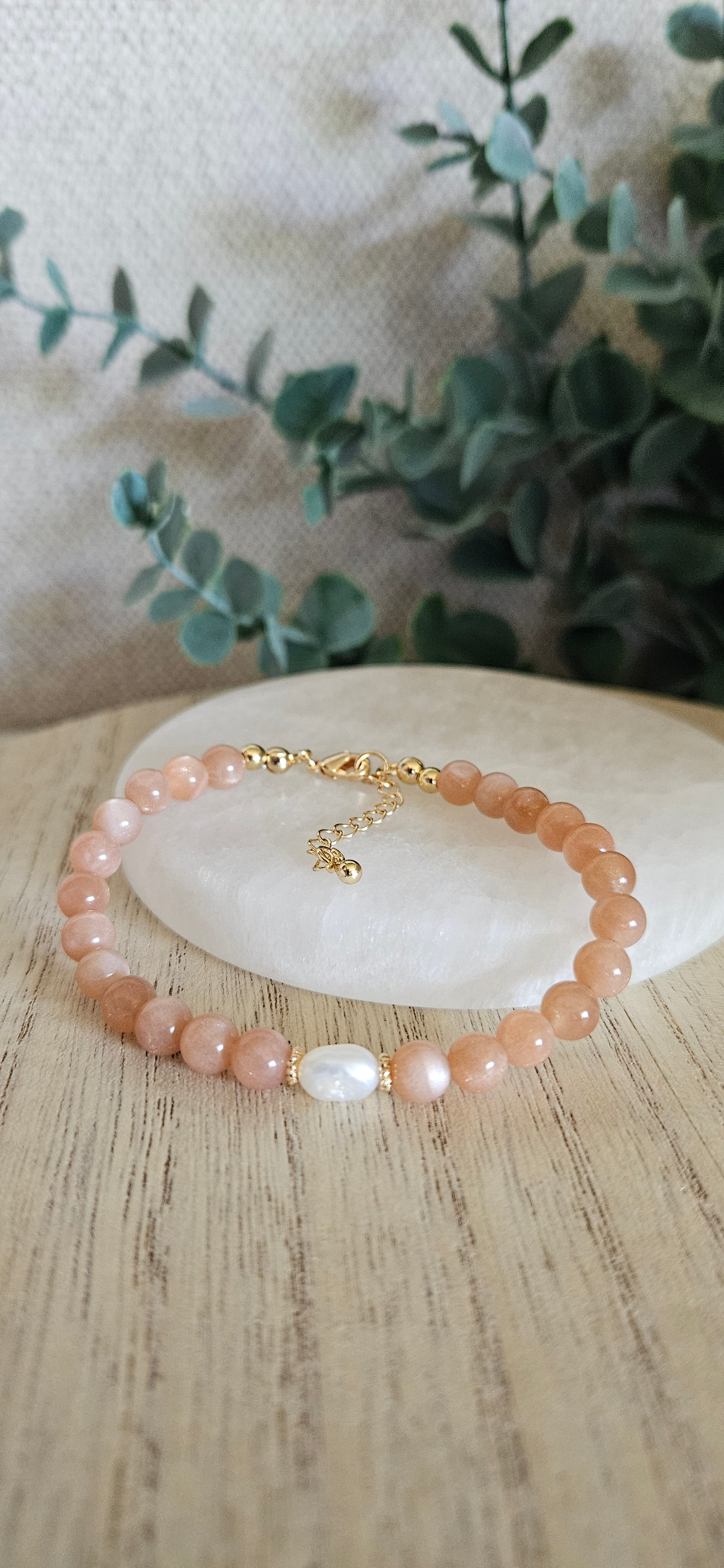 orange gemstone bracelet with a pearl on a selenite plate