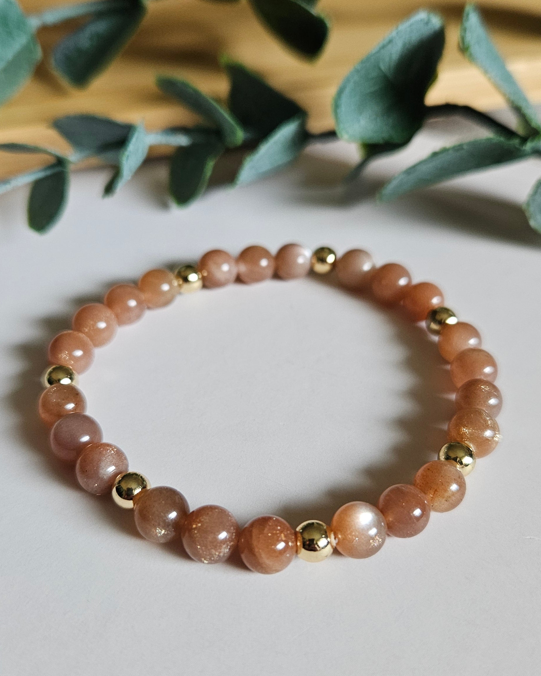 orange beaded bracelet with gold accents on a white background