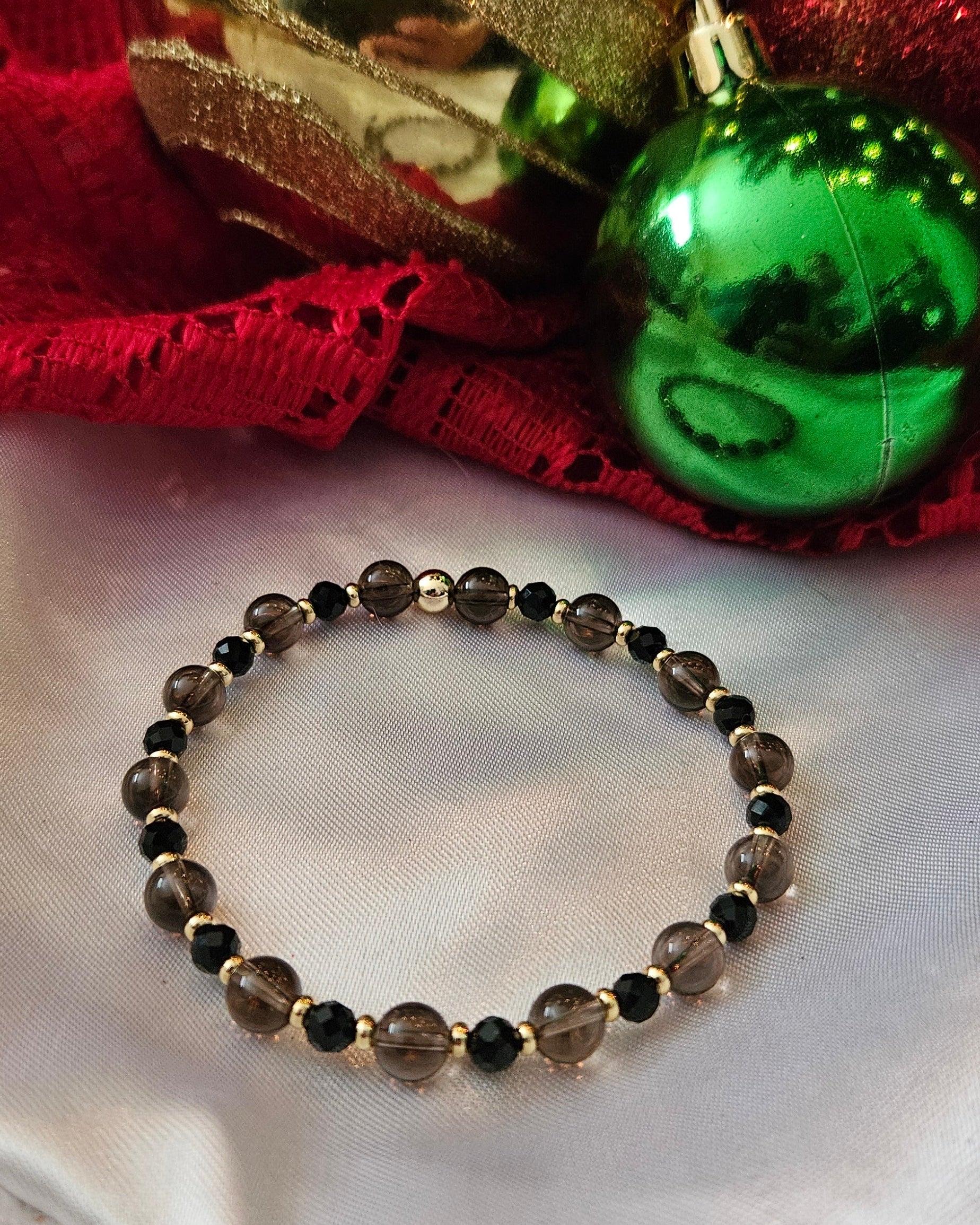 Bracelet on a white surface with decorative red and gold objects in the background