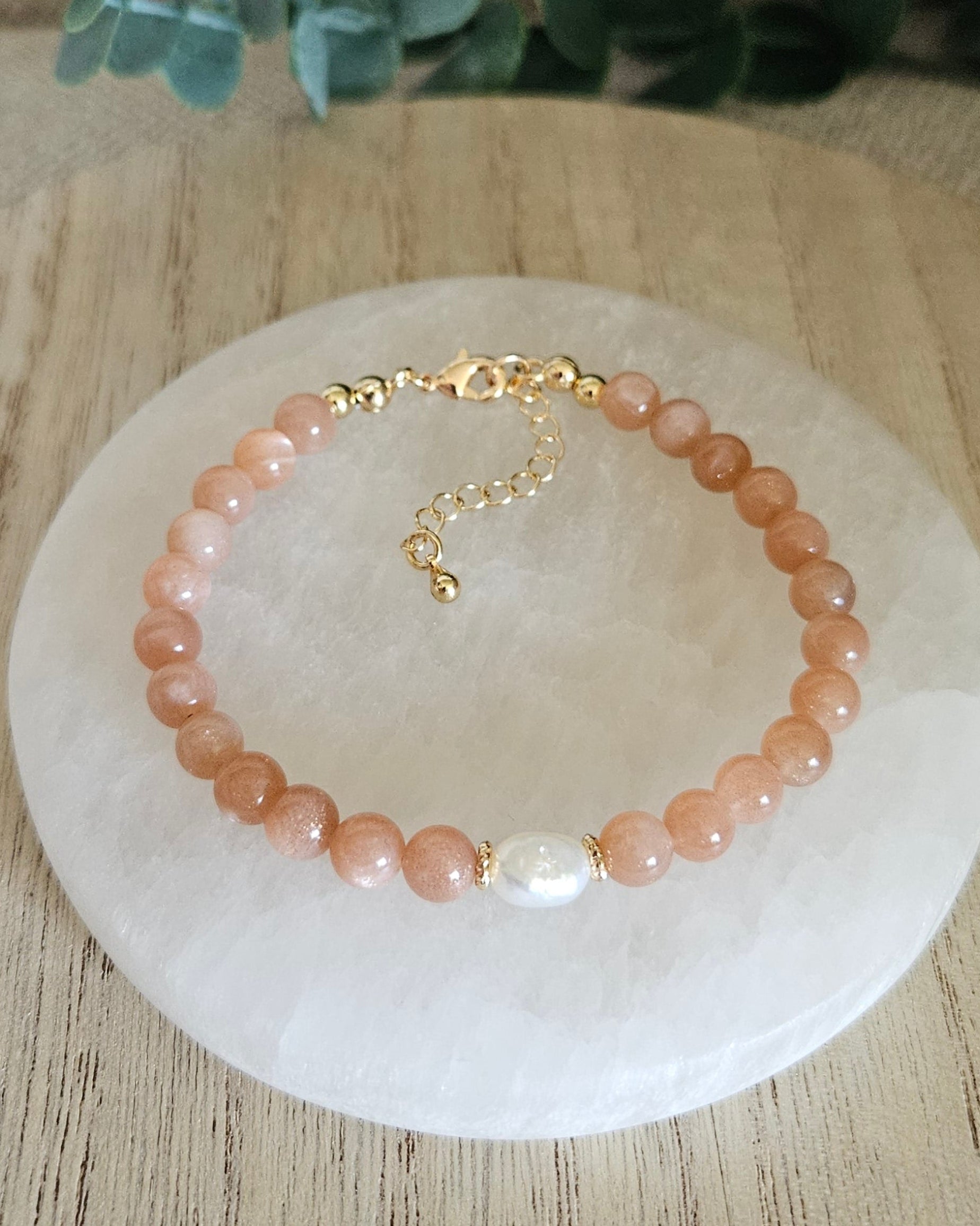 sunstone bracelet with pearl focal on a selenite plate with eucalyptus in the background