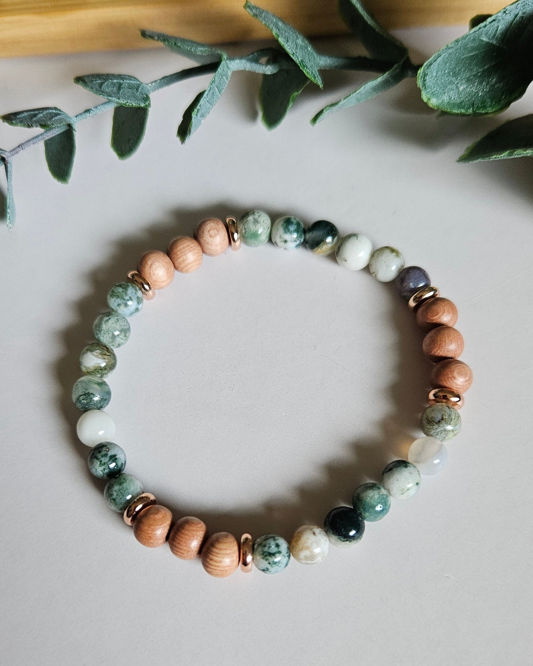 Beaded bracelet with natural stones on a light surface with green leaves
